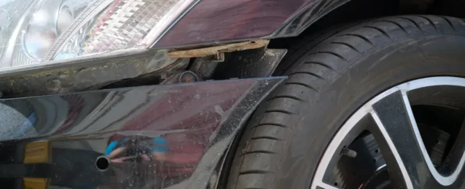 dented-car-with-damaged-fender-parked-on-city-street